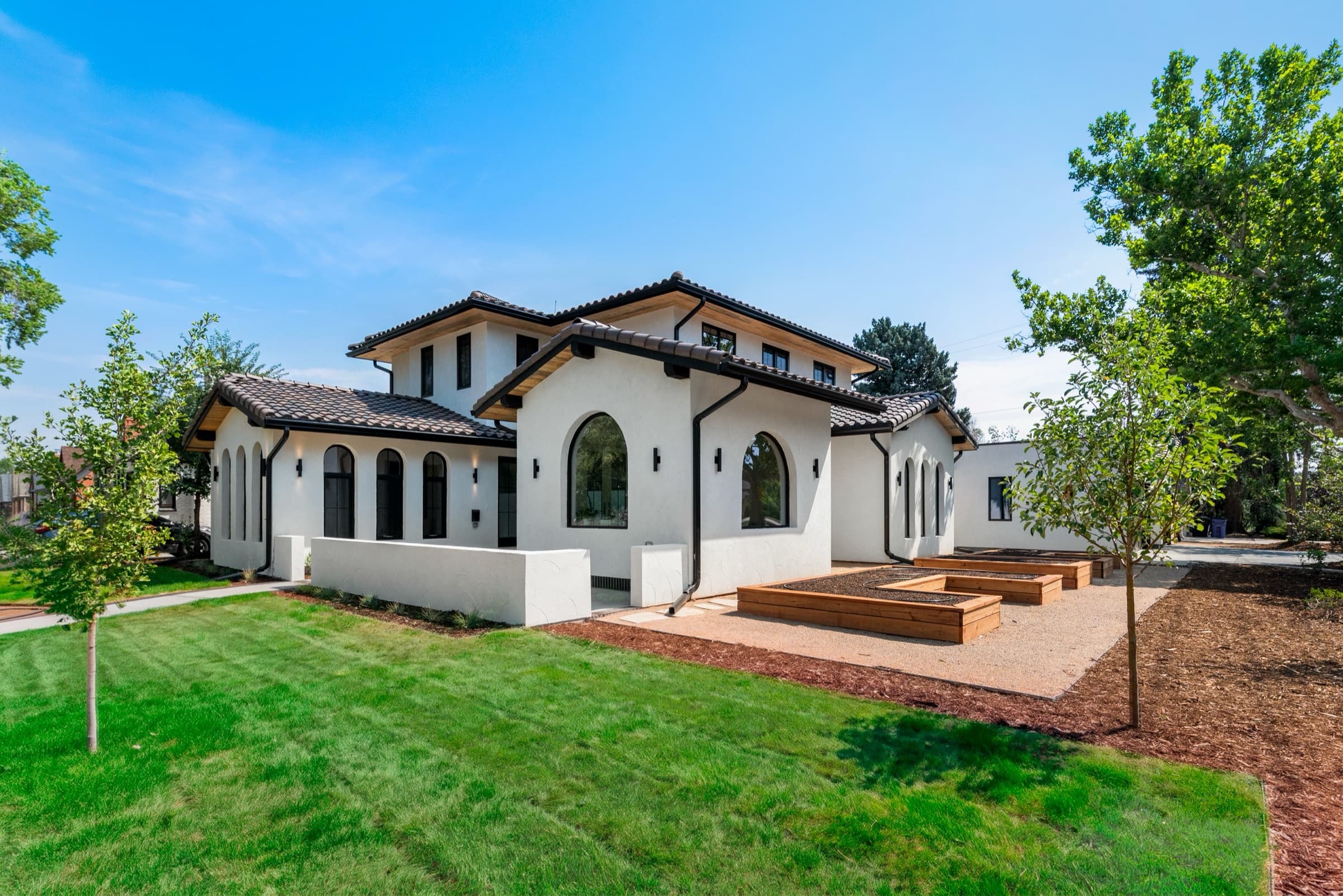 White stucco home with a clay tile roof, arched windows and cedar planter beds