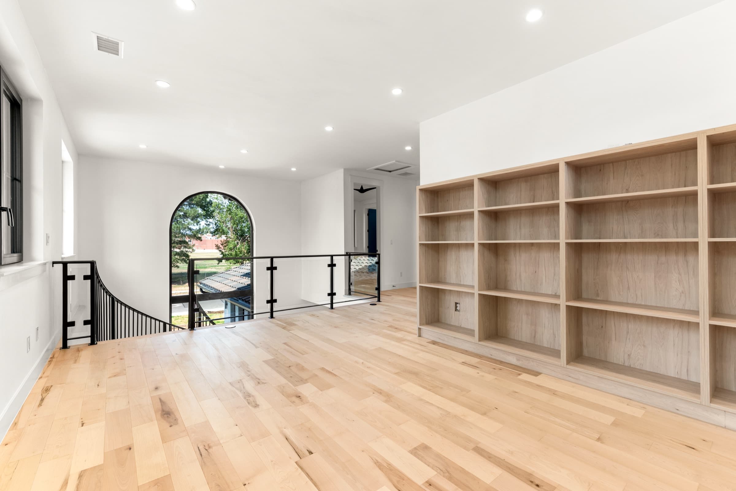 Upper loft with built-in shelving and an arched window