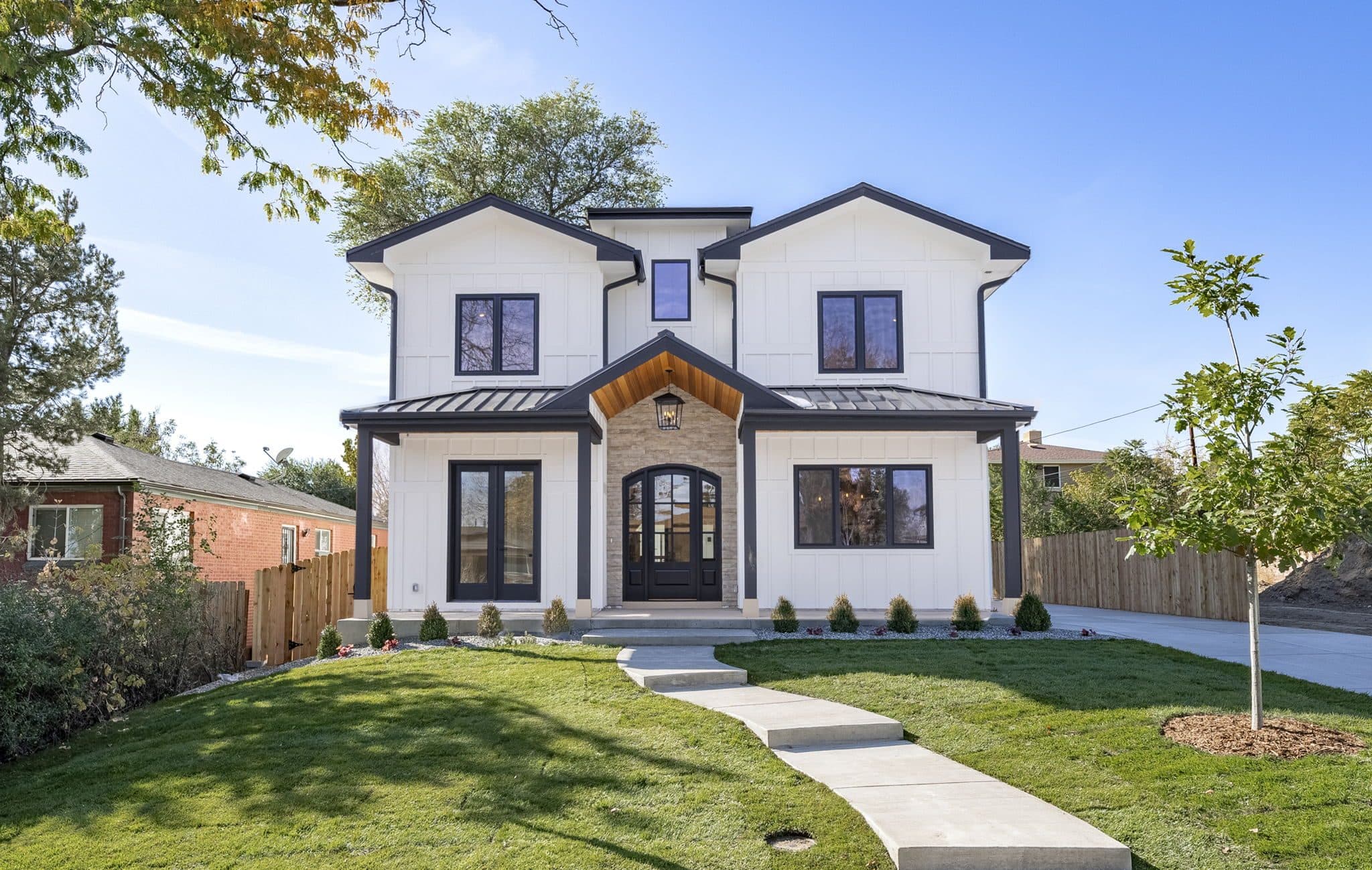 Two-storey white home with black-framed windows and a timber-clad entry gable